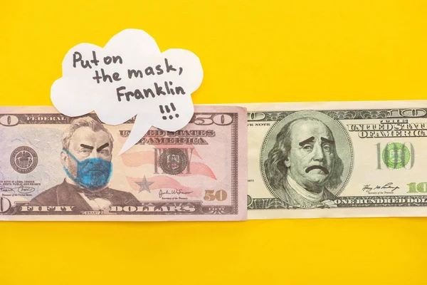 Top view of banknotes with drawn medical mask and face expressions near speech bubble on yellow background — Stock Photo