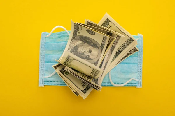 Top view of dollars and medical mask on yellow background — Stock Photo