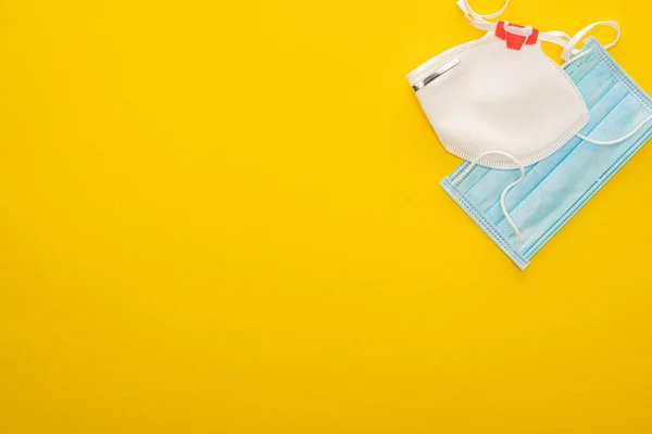 Draufsicht auf medizinische und Sicherheitsmasken auf gelbem Hintergrund — Stockfoto