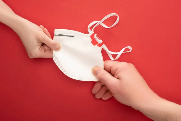 Partial view of woman and man sharing safety mask on red background — Stock Photo