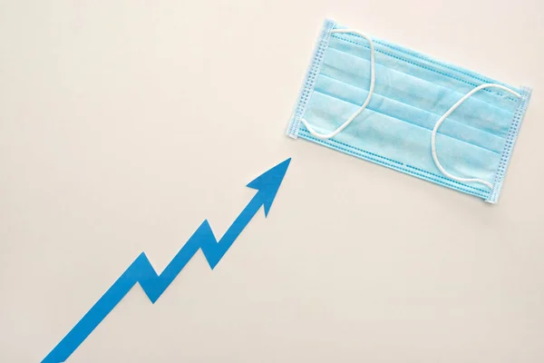 Вид зверху блакитної стріли і медична маска на білому тлі — стокове фото