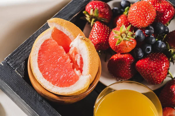 Close up view of french breakfast with grapefruit, orange juice, berries on wooden tray — Stock Photo