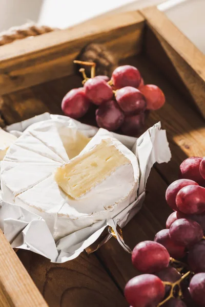 Nahaufnahme des französischen Frühstücks mit Camembert und Trauben auf Holztablett — Stockfoto