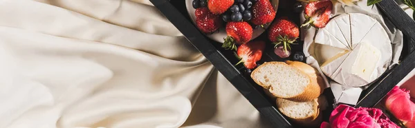 Top view of french breakfast with Camembert, berries and baguette on tray on white tablecloth, panoramic shot — Stock Photo