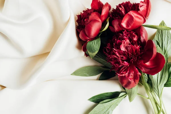 Top view of bouquet of red peonies on white cloth — Stock Photo