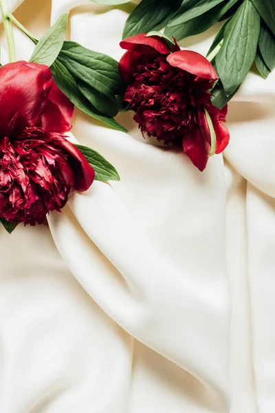 Vista dall'alto di mazzo di peonie rosse su panno bianco — Foto stock