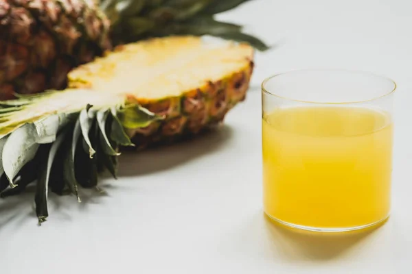 Selective focus of fresh pineapple juice near cut delicious fruit on white background — Stock Photo