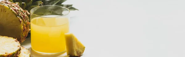 Fresh pineapple juice near cut delicious fruit on white background, panoramic orientation — Stock Photo