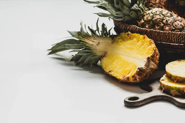 Fresh cut delicious pineapple on wooden cutting board and in basket on white background — Stock Photo