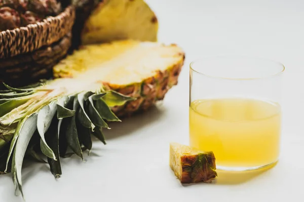 Vista da vicino del succo d'ananas fresco vicino tagliare deliziosi frutti su sfondo bianco — Foto stock