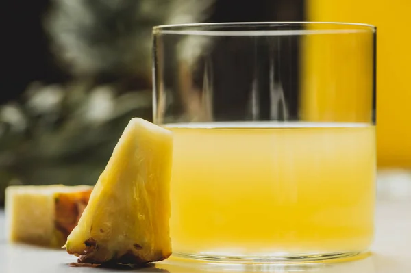 Nahaufnahme von frischem Ananassaft in der Nähe köstlicher Fruchtscheiben — Stockfoto