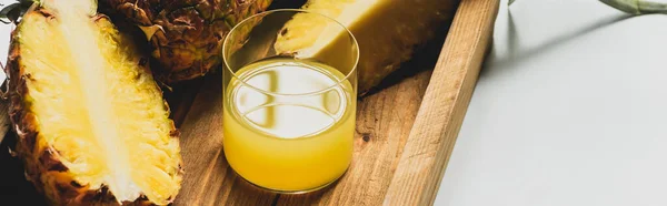 Fresh pineapple juice and cut delicious fruit on wooden tray on white background, panoramic orientation — Stock Photo