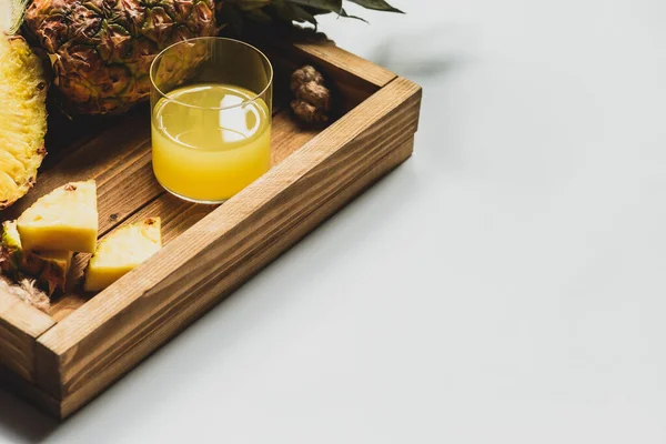 Suco de abacaxi fresco e cortar frutas deliciosas na bandeja de madeira no fundo branco — Fotografia de Stock