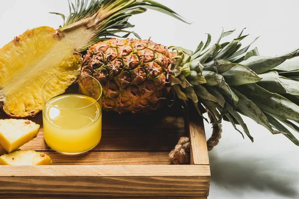 Свежий ананасовый сок и срезать вкусные фрукты на деревянном подносе на белом фоне — стоковое фото