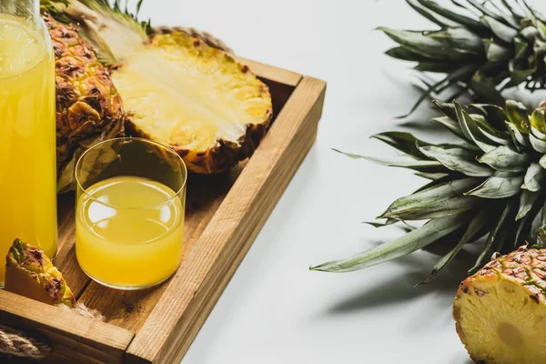 Fresh pineapple juice and cut delicious fruit on wooden tray on white background — Stock Photo