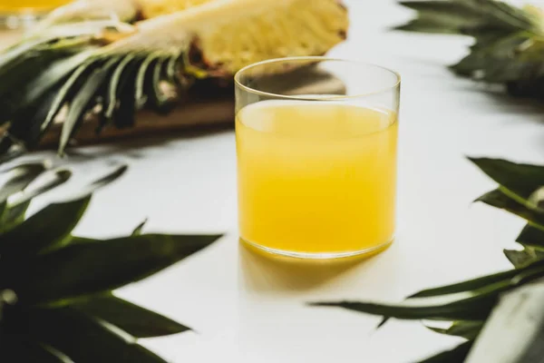 Selective focus of fresh pineapple juice near cut delicious fruit on cutting board on white background — Stock Photo