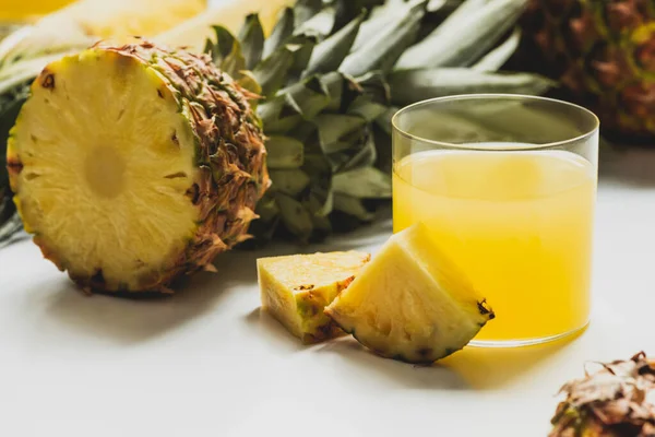 Succo d'ananas fresco vicino a tagliare deliziosi frutti su sfondo bianco — Foto stock