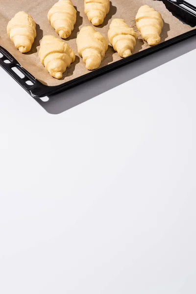 Croissants crus na bandeja de cozimento no fundo branco — Fotografia de Stock