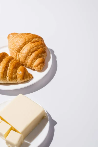 Rohe Croissants auf hölzernem Schneidebrett neben Butter, Eier auf weißem Hintergrund — Stockfoto