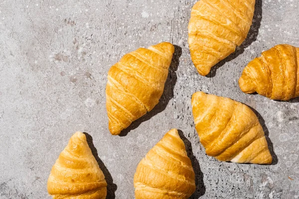 Vista superior de croissants cozidos no forno fresco na superfície cinzenta concreta — Fotografia de Stock