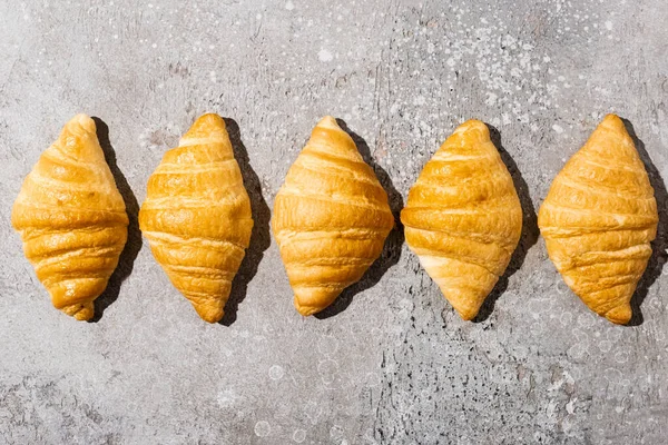 Posa piatta con croissant appena sfornati su superficie grigio cemento — Foto stock