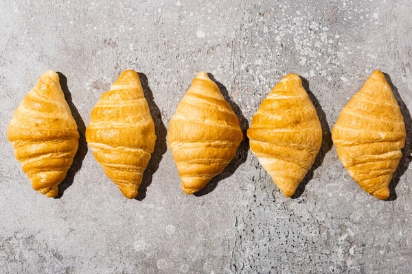 Couche plate avec des croissants frais cuits au four sur la surface gris béton — Photo de stock