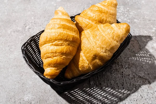Croissants cozidos no forno fresco na cesta na superfície cinzenta concreta — Fotografia de Stock