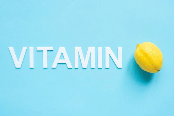 Ansicht der reifen gelben Zitrone und des Wortes Vitamin auf blauem Hintergrund — Stockfoto