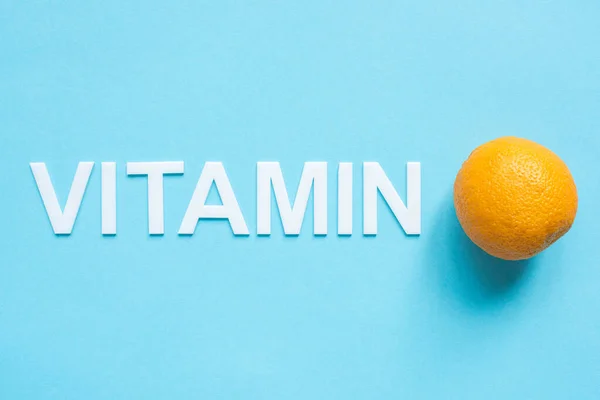Vista superior de laranja madura e vitamina palavra no fundo azul — Fotografia de Stock