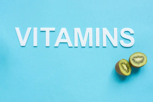 Draufsicht auf reife Kiwi und Word-Vitamine auf blauem Hintergrund — Stockfoto