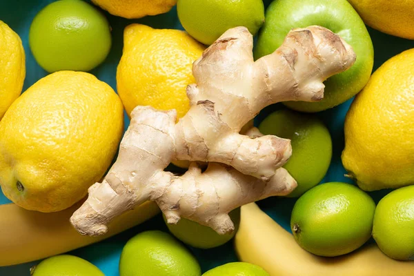 Vue du dessus de la racine de gingembre sur citrons jaunes, bananes, pommes vertes et citrons verts — Photo de stock