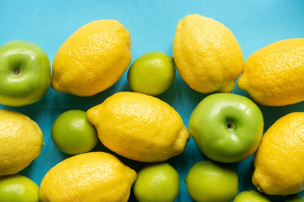 Vista superior de limones amarillos maduros y manzanas verdes y limas sobre fondo azul - foto de stock