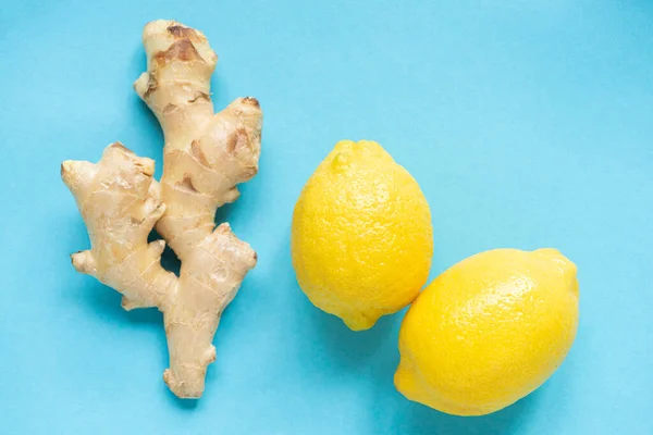Top view of ripe yellow lemons and ginger root on blue background — Stock Photo