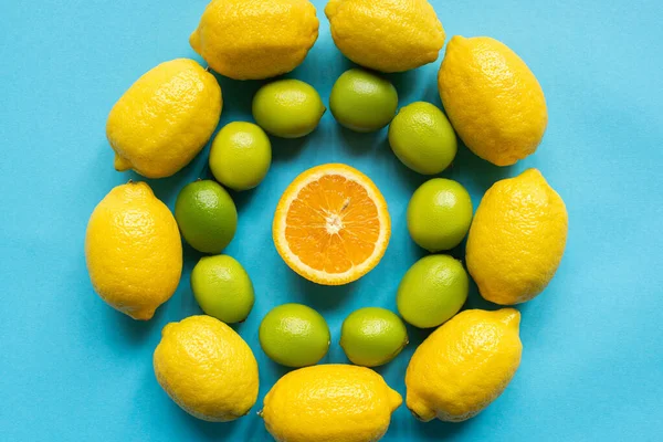 Draufsicht auf reife gelbe Zitronen, Orange und Limetten, kreisförmig auf blauem Hintergrund angeordnet — Stockfoto