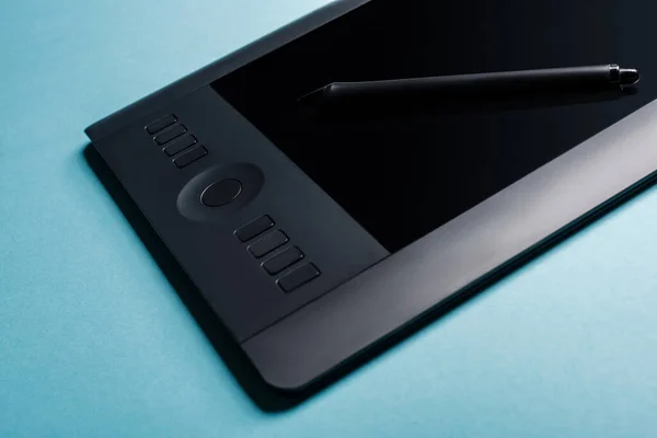 Close up view of graphics tablet and stylus on blue surface — Stock Photo