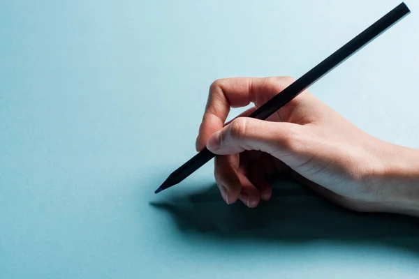 Ausgeschnittene Ansicht eines Designers, der Bleistift auf blauer Oberfläche hält — Stockfoto