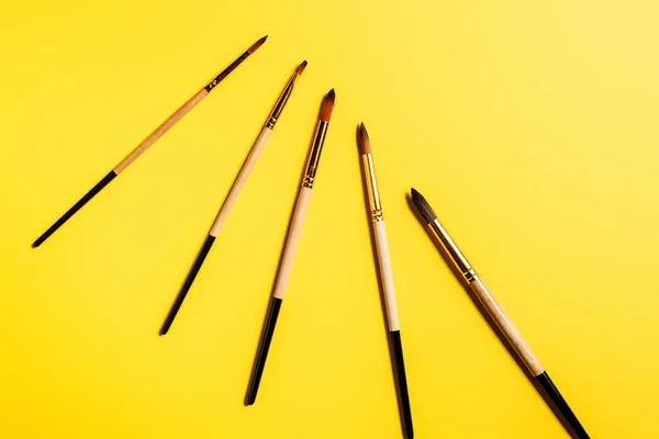 Top view of paintbrushes on yellow background with copy space — Stock Photo