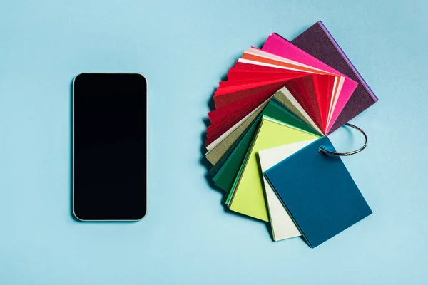 Top view of smartphone and color samples on blue surface — Stock Photo