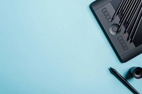 Top view of color pencils on graphics tablet and stylus on blue background — Stock Photo