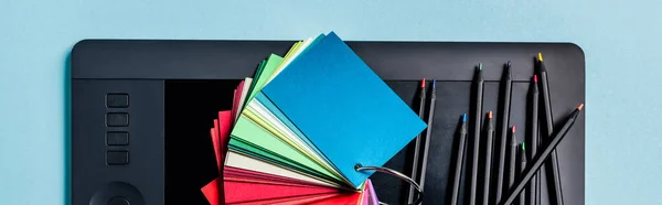 Panoramic crop of color samples, graphics tablet and color pencils on blue background — Stock Photo