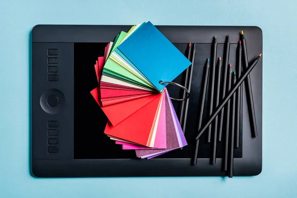 Visão superior de amostras de cores e lápis no tablet gráfico no fundo azul — Fotografia de Stock