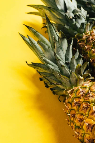 Fresh ripe pineapples with green leaves on yellow background — Stock Photo