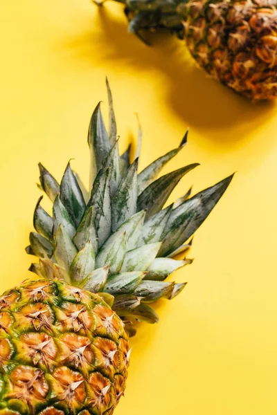 Enfoque selectivo de piñas frescas maduras con hojas verdes sobre fondo amarillo — Stock Photo