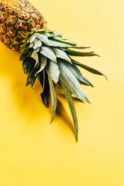 Ananas fresco maturo con foglie verdi su fondo giallo — Foto stock