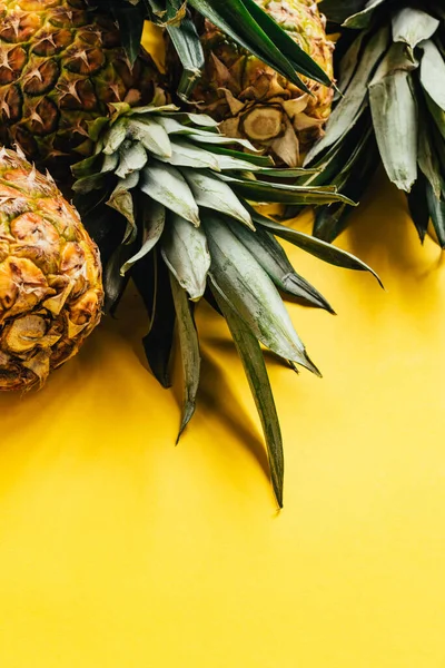 Piñas frescas maduras con hojas verdes sobre fondo amarillo - foto de stock