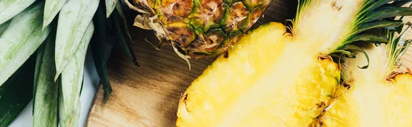 Top view of juicy pineapple halves on wooden cutting board, panoramic shot — Stock Photo