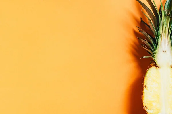 Vue du dessus de l'ananas mûr coupé avec des feuilles vertes sur fond orange — Photo de stock