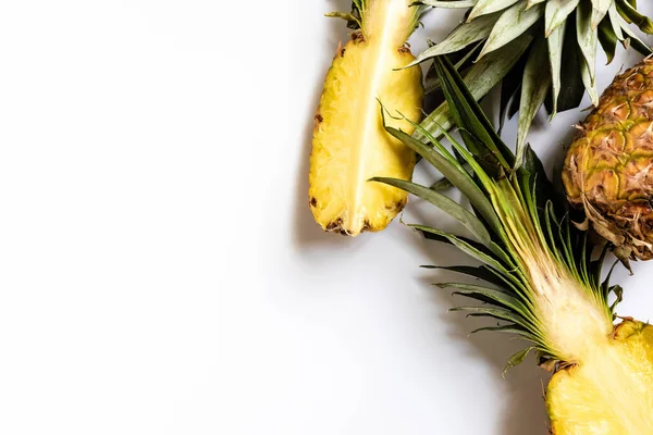 Top view of cut and whole ripe pineapples with green leaves on white background — Stock Photo