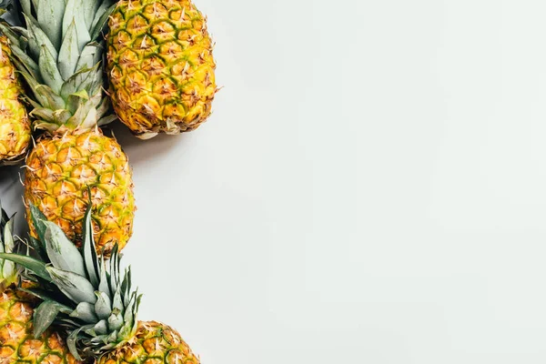 Vue de dessus des ananas mûrs avec des feuilles vertes sur fond blanc — Photo de stock