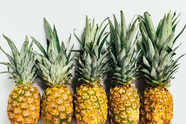 Plat posé avec des ananas frais mûrs avec des feuilles vertes sur fond blanc — Photo de stock